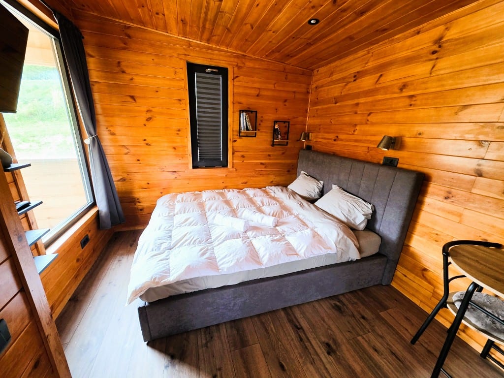 The bedroom, with an upholstered headboard, bedside shelves and a hillside view