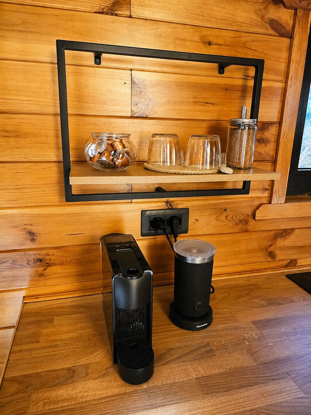 Nespresso coffee machine with capsules and a milk frother on the kitchenette counter