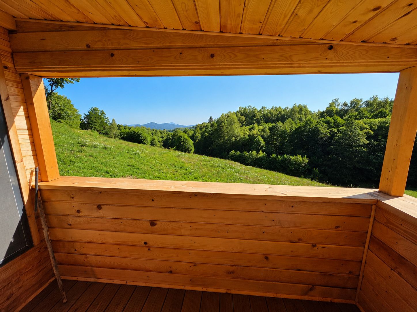 The view across the meadow to the ridgeline, framed by the terrace roof